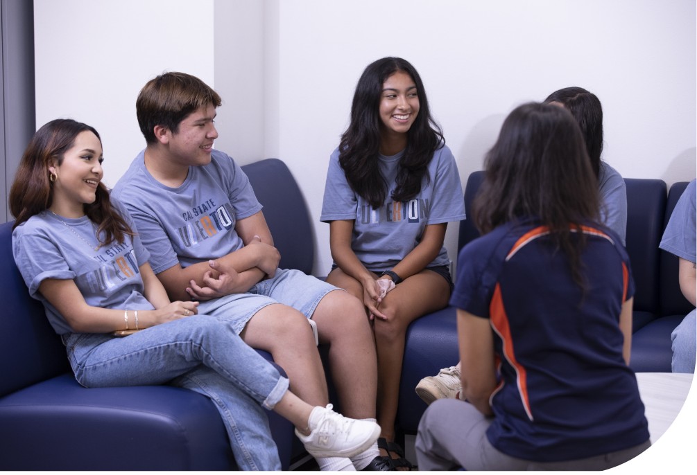 group of five young college students sitting together wearing cal state fullerton attire